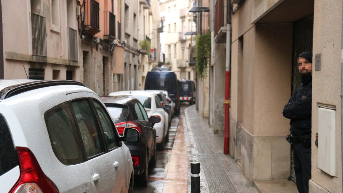Un agente de los Mossos y dos furgones en la calle San Sebastià d'Igualada, donde se está registrando el domicilio del detenido.