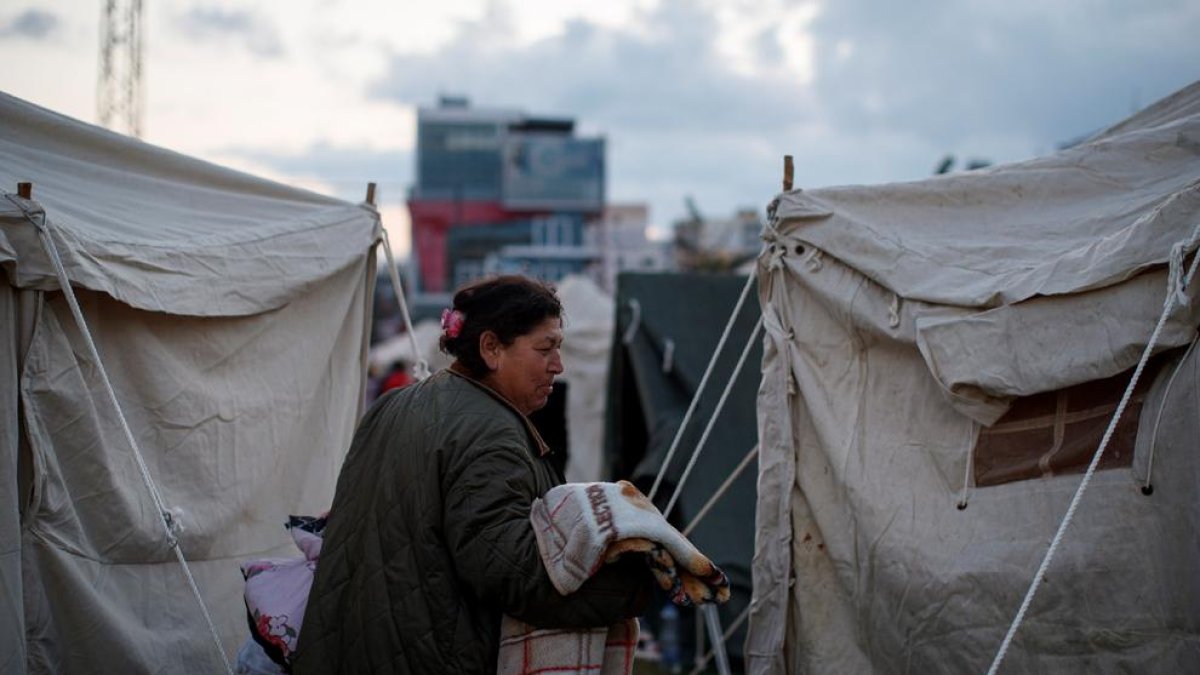 Una mujer camina entre las tiendas de un campamento.
