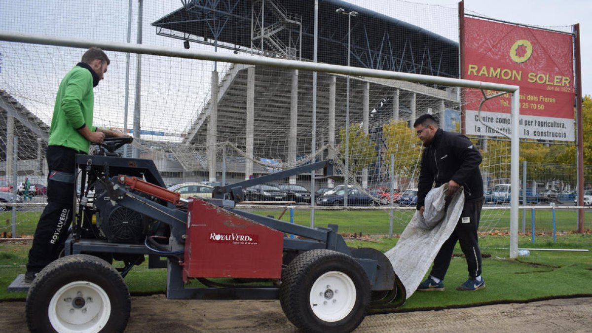 Dos operaris de l’empresa Royal Verd col·loquen els pans d’herba al camp Annex al Camp d’Esports.