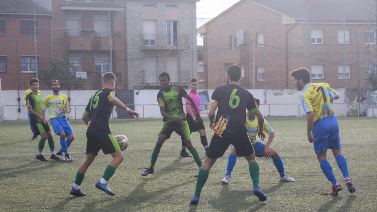 Un árbitro, al fondo, dirigiendo un partido del fútbol leridano.