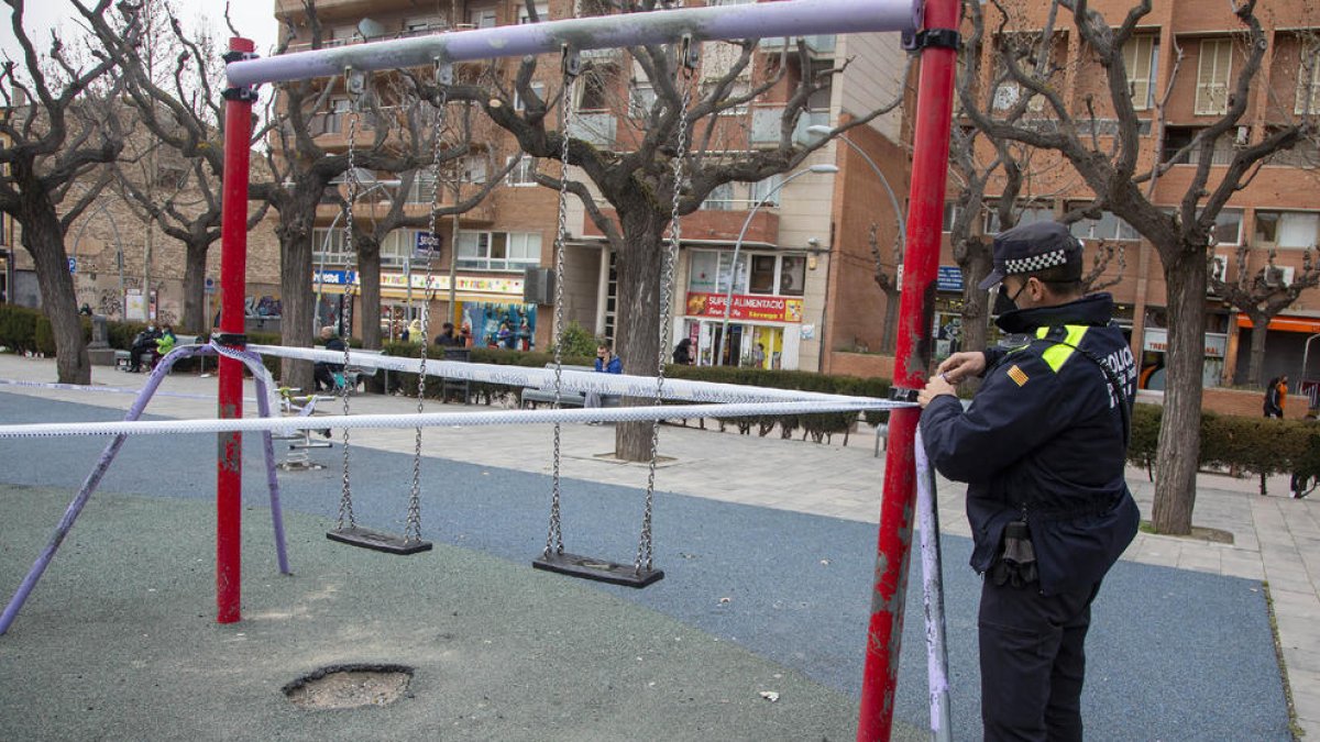 Un agente de la policía de Tàrrega precinta un parque infantil tras decretarlo el ayuntamiento.