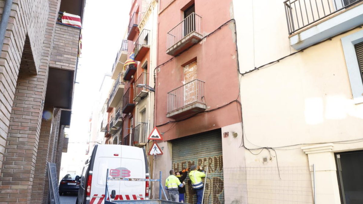 Operaris tornant a tapiar l’entrada a l’edifici calcinat.