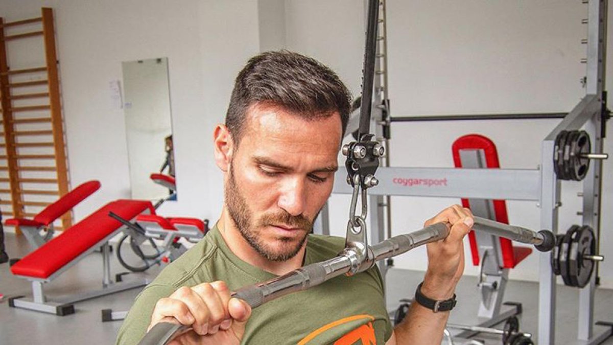 Saul Craviotto trabajando en el gimnasio con máquinas de musculación y pesas.