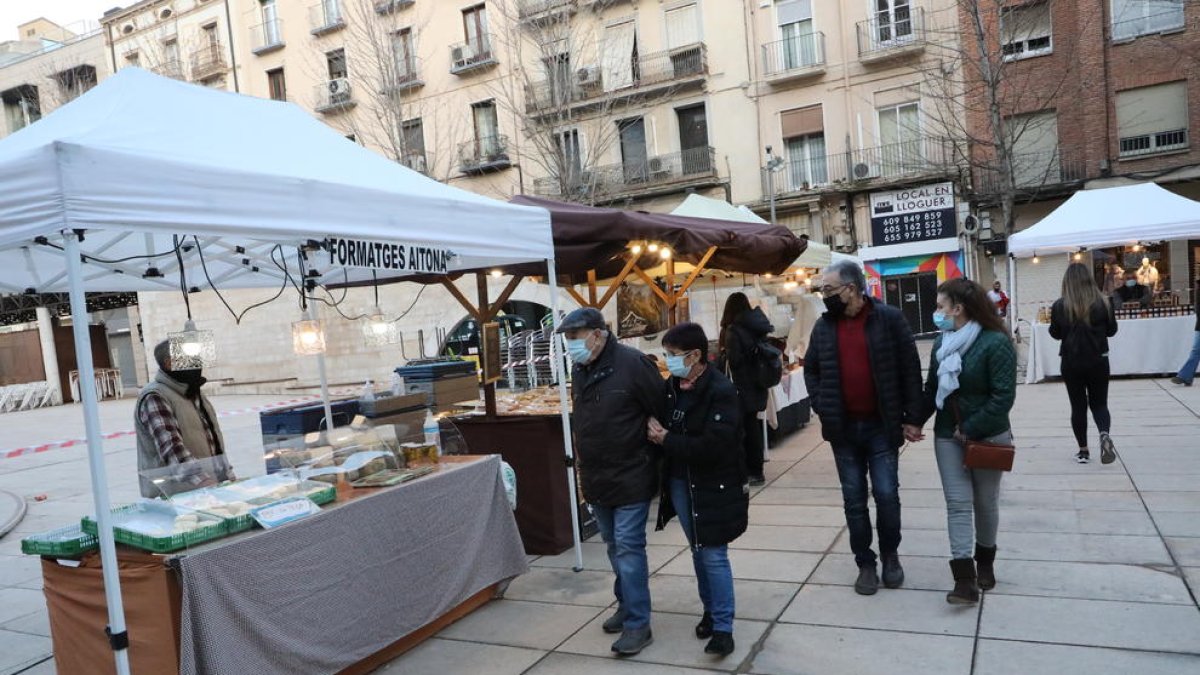 Visitants en una de les parades del mercat, envoltat amb una cinta per controlar l’aforament.
