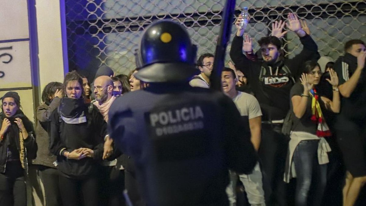 Un mosso ante un grupo de manifestantes, en la noche de la huelga del 18-O, en Barcelona.