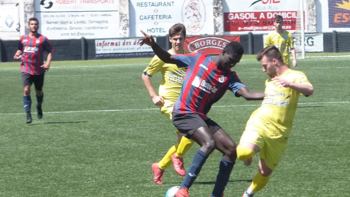 Sylla, del Tàrrega, intenta controlar una pilota davant de l’oposició de dos jugadors del Cambrils.