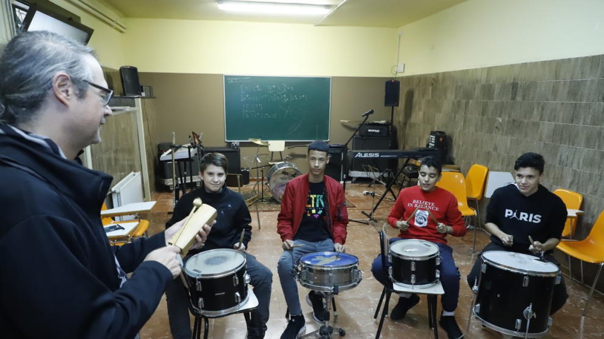 Cuatro alumnos siguiendo las instrucciones del profesor en una sesión de musicoterapia.