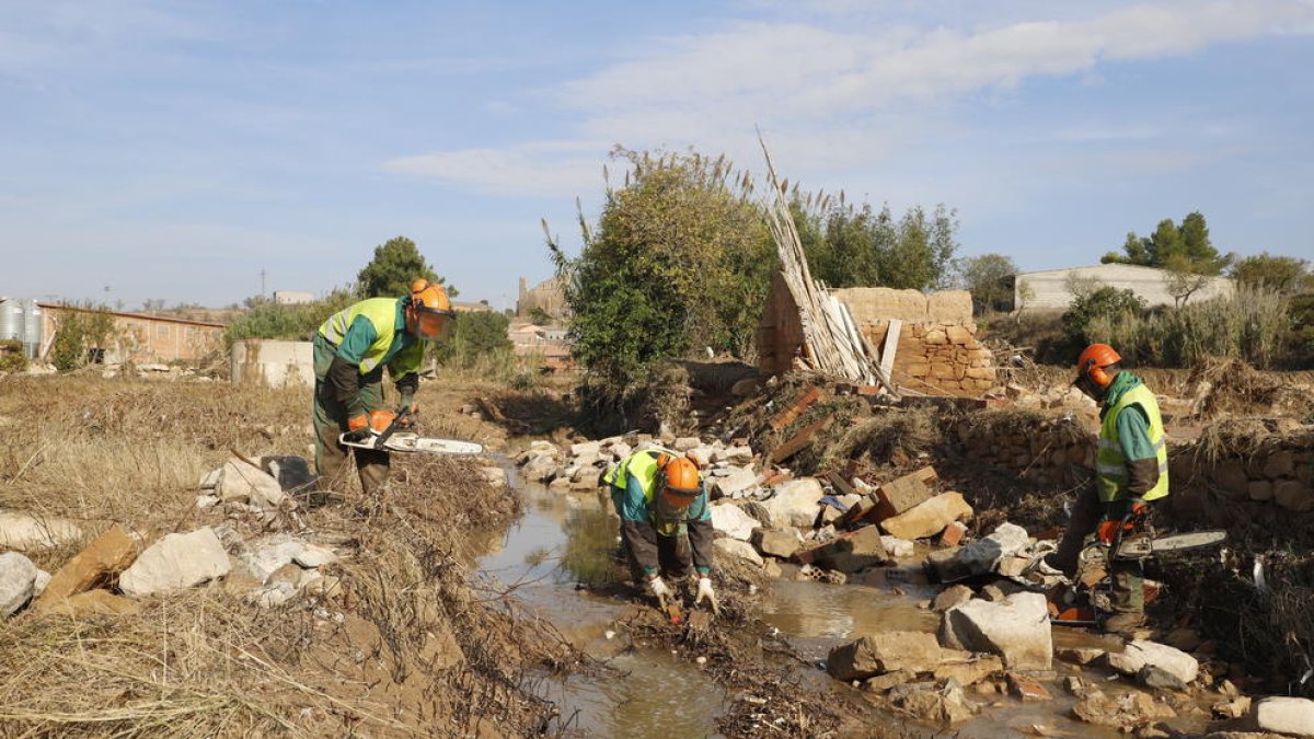 Imagen de los operarios de la CHE trabajando ayer para reparar las obstrucciones en el caudal del río en L’Albi tras las inundaciones.