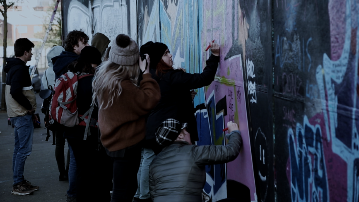 Un grupo de jóvenes pinta un mural en una calle de Belfast.