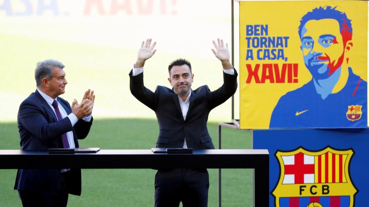 El nuevo entrenador del FC Barcelona, Xavi Hernández, junto al presidente del club, Joan Laporta , saluda a los aficionados que se han citado en las gradas del Camp Nou durante el acto de presentacion como entrenador blaugrana.