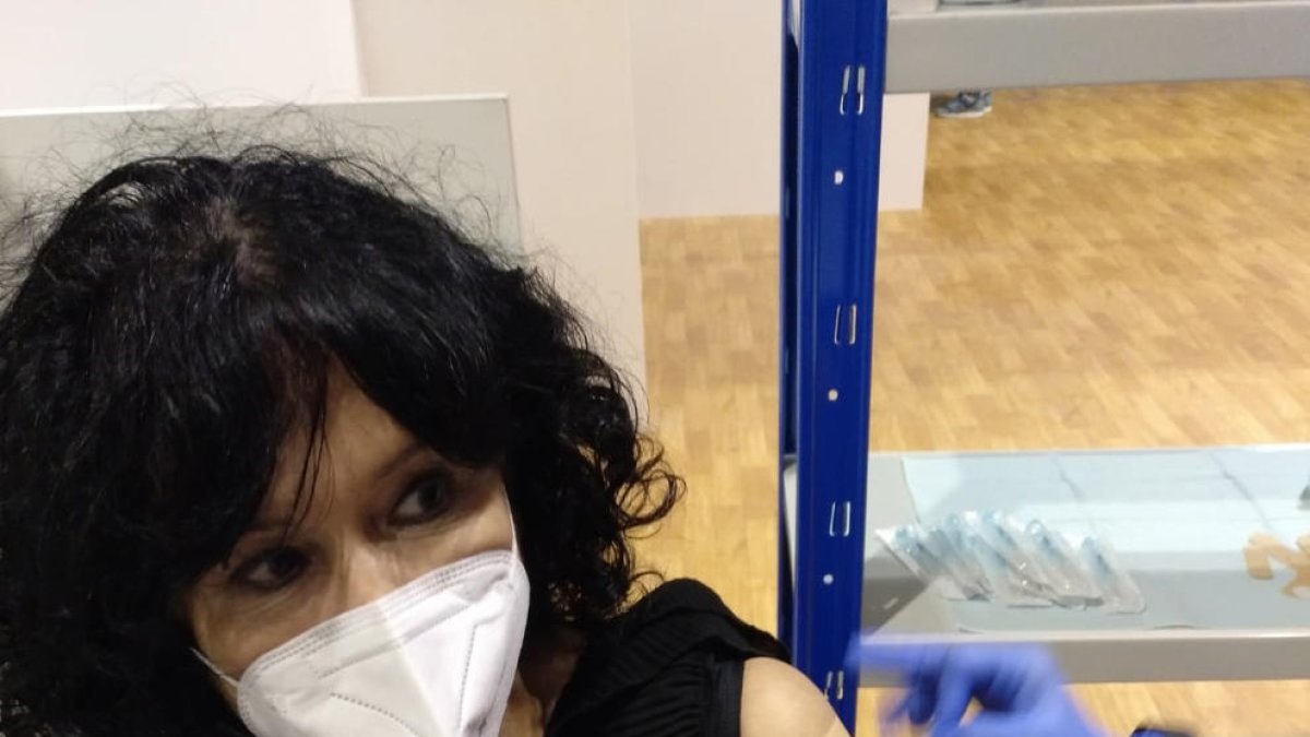 La farmacéutica Sílvia Pallàs recibe la vacuna y a la derecha, colas ante el pabellón Onze de Setembre.