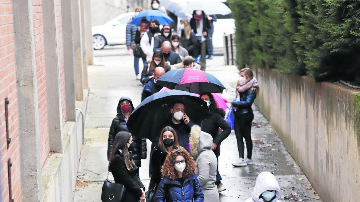 La farmacèutica Sílvia Pallàs rep la vacuna i a la dreta, cues al davant del pavelló Onze de Setembre.