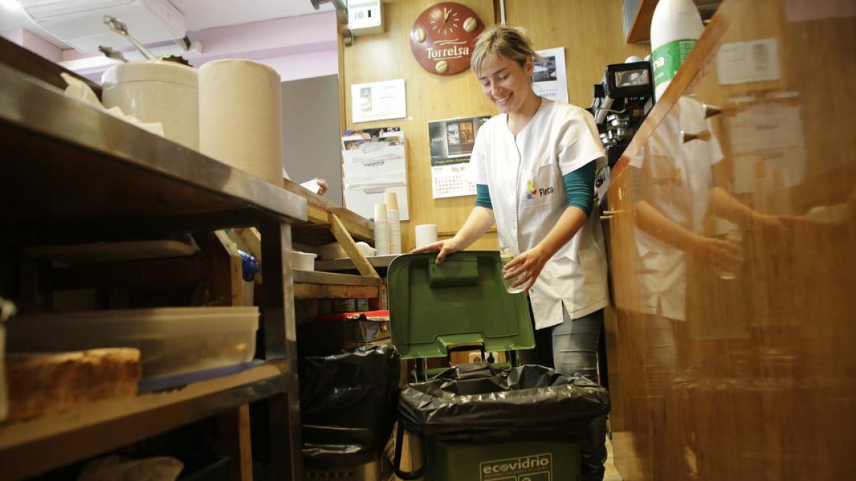 Una treballadora tira una botella al contenidor d’Ecovidrio.