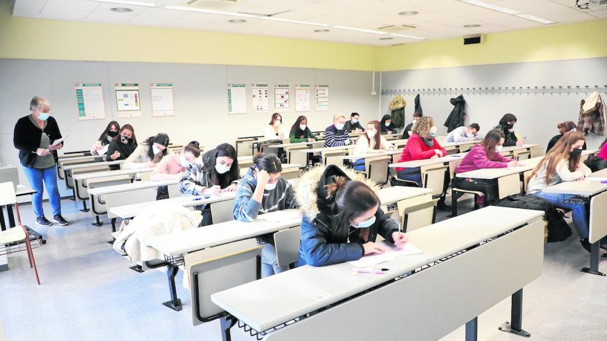 Alumnes d’Infermeria fent un examen presencial, alguns amb abric, ahir al matí.