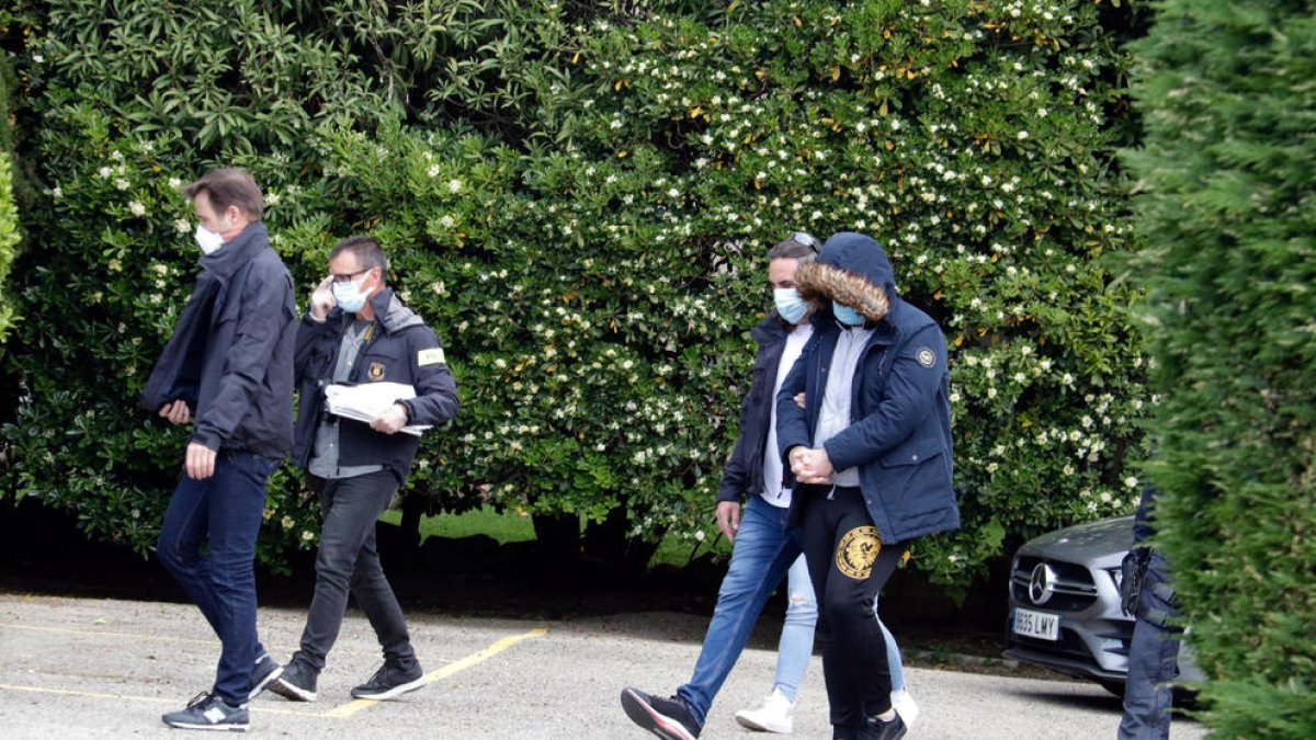 Un agente de los mossos traslada a uno de los detenidos.