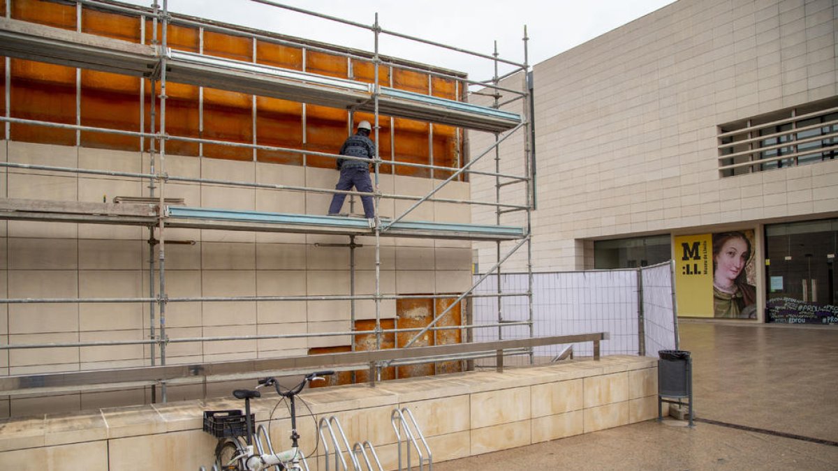 Un operari treballant ahir en una de les façanes afectades, en la qual ja s’han retirat les plaques de pedra de les files superiors.