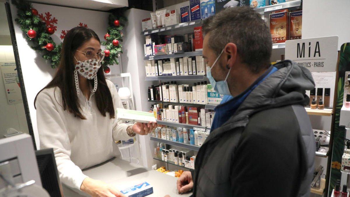 Una empleada de la farmàcia Anadón Solé mostra alguns tests d’antígens a un client, ahir.