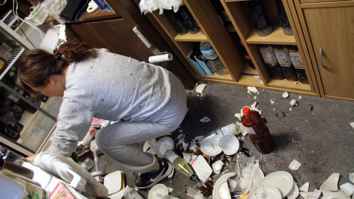 Una dona inspecciona els desperfectes ocasionats pel terratrèmol al seu local.