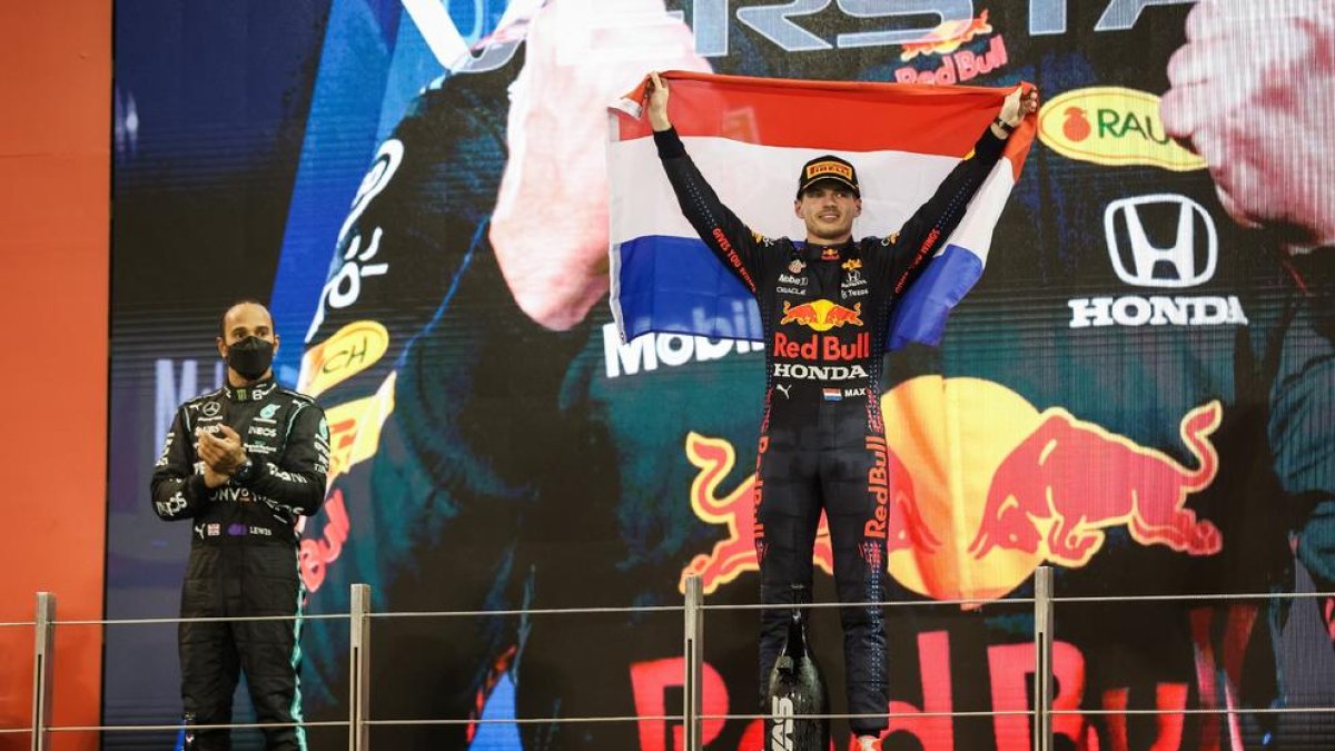 Max Verstappen celebra al podi el seu primer títol mundial de Fórmula 1, amb Lewis Hamilton al costat mentre aplaudeix.