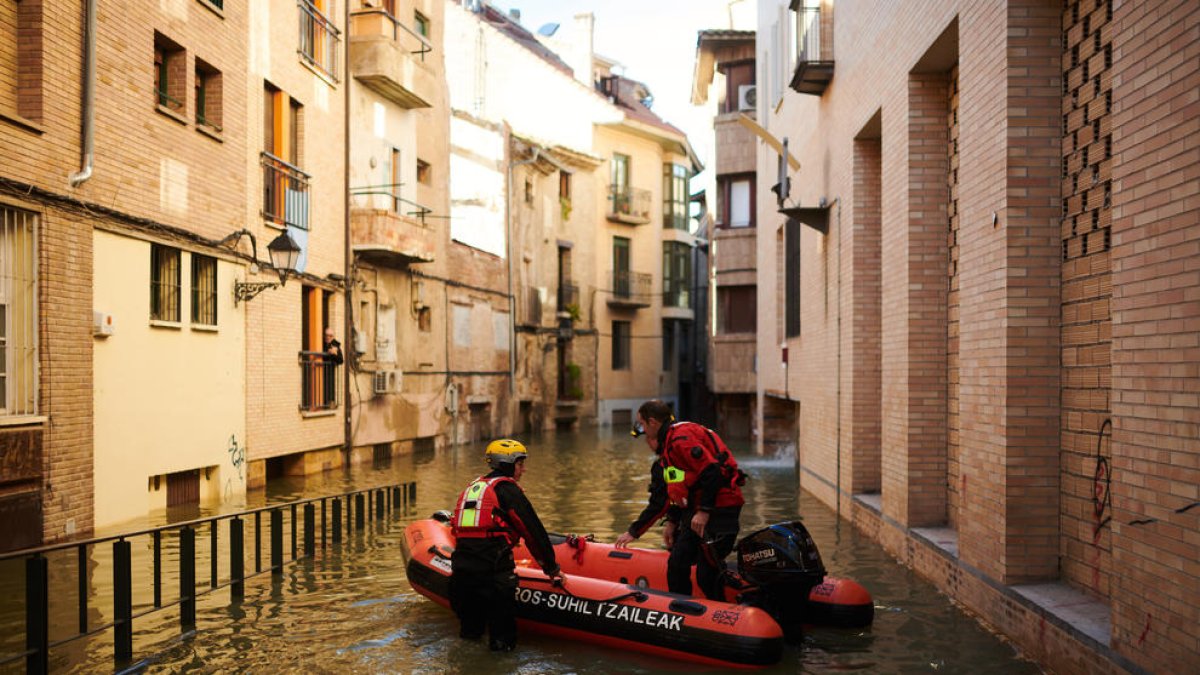 Dos bomberos navegan por una de las calles anegadas de Tudela.