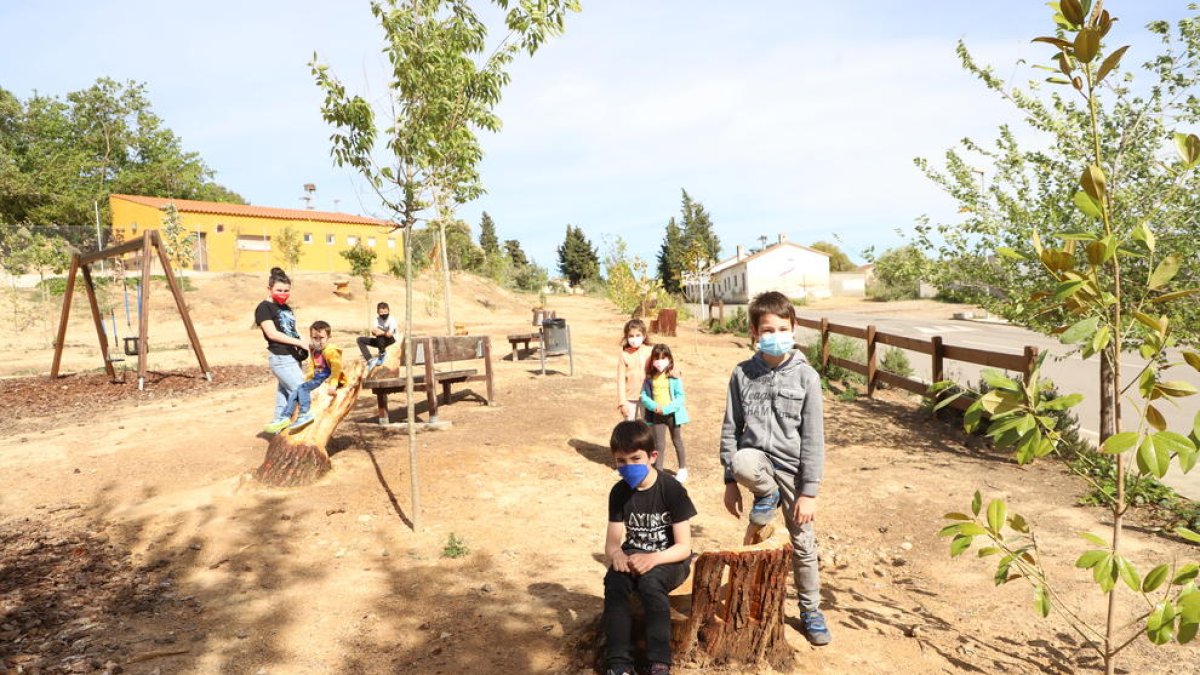Varios niños de Sucs prueban los nuevos bancos hechos con los tocones de pinos en el parque del Vilot.