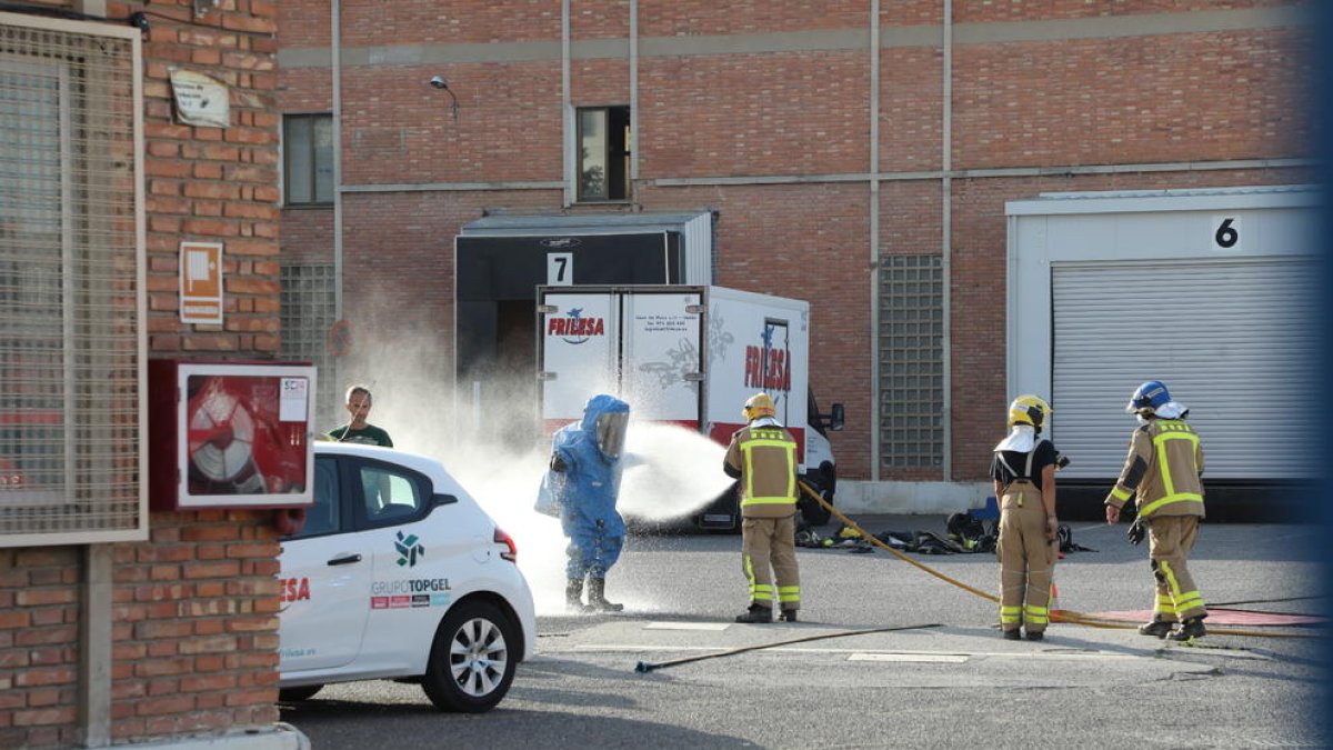 Bomberos limpiando el equipo de protección de un compañero.