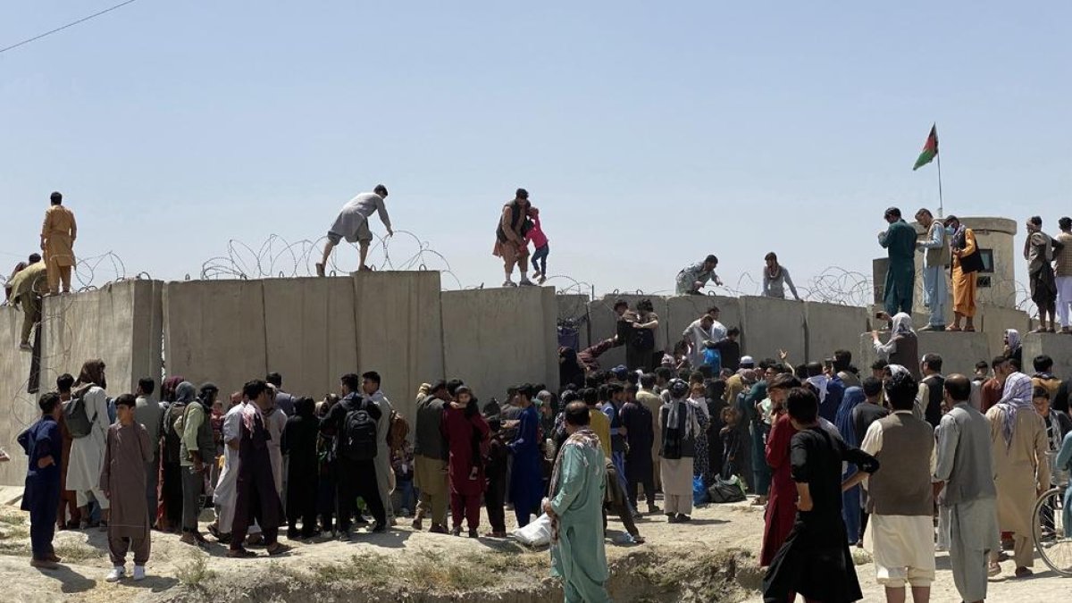 Desenes d’afganesos intenten entrar a les pistes de l’aeroport de Kabul saltant els filats.