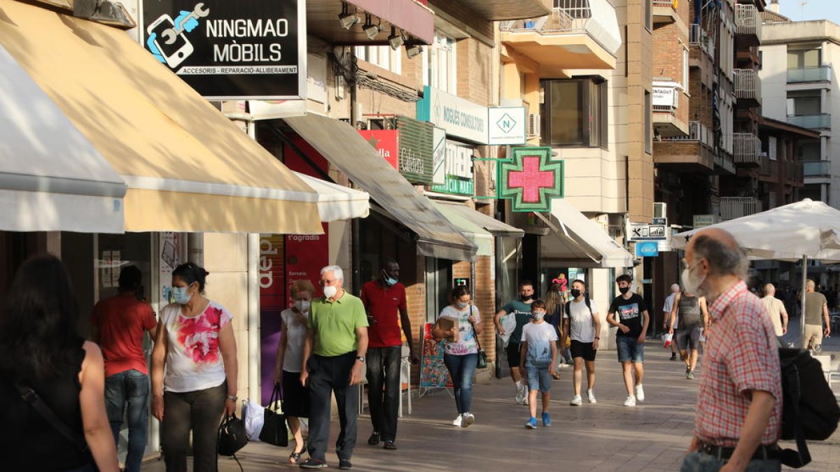 Diverses persones passejant ahir per l’Eix Comercial amb màscara.