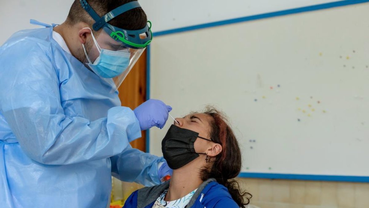 Un sanitario efectúa una prueba PCR a una mujer durante un cribado.