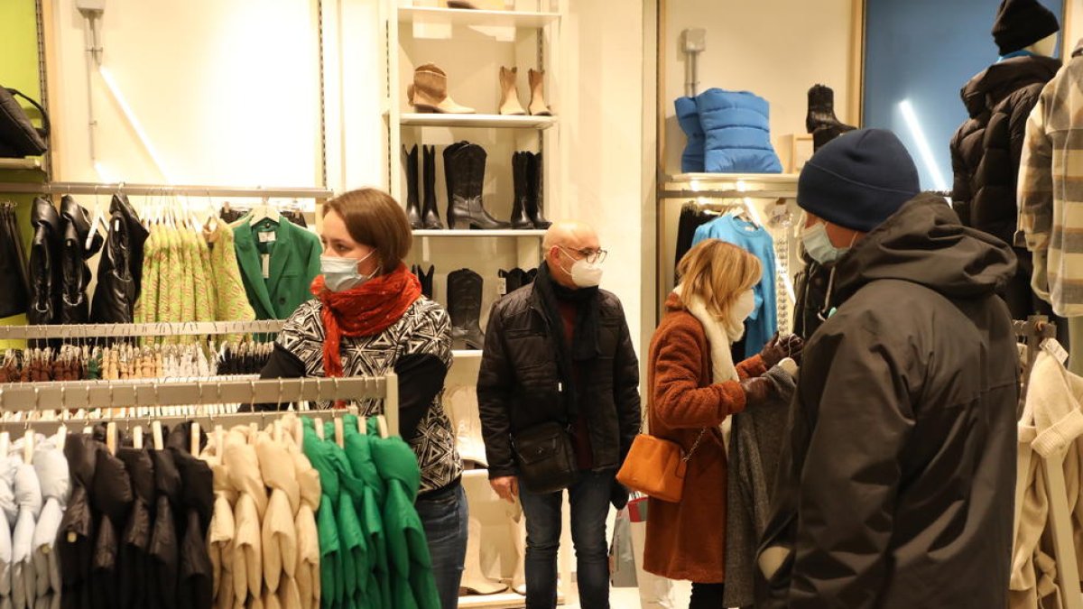 Varias personas miran ropa en el interior de una tienda del Eix Comercial.