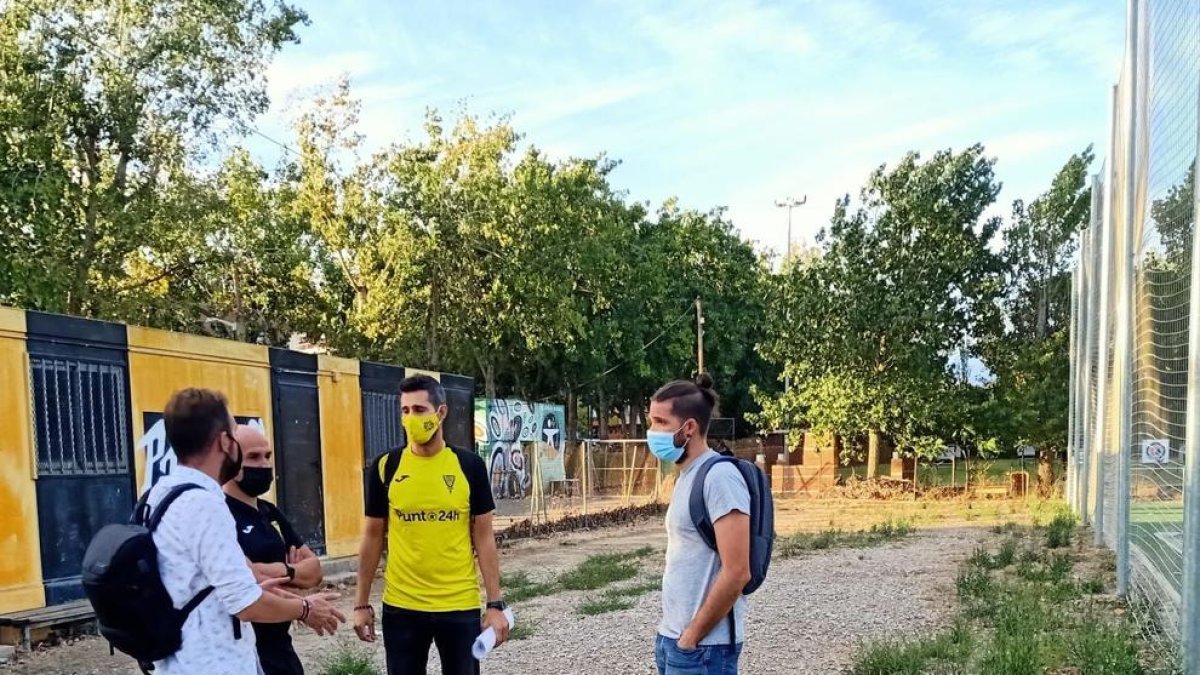 Amor, Vidal, García i un representant del club conversen sobre la zona que es vol pavimentar.