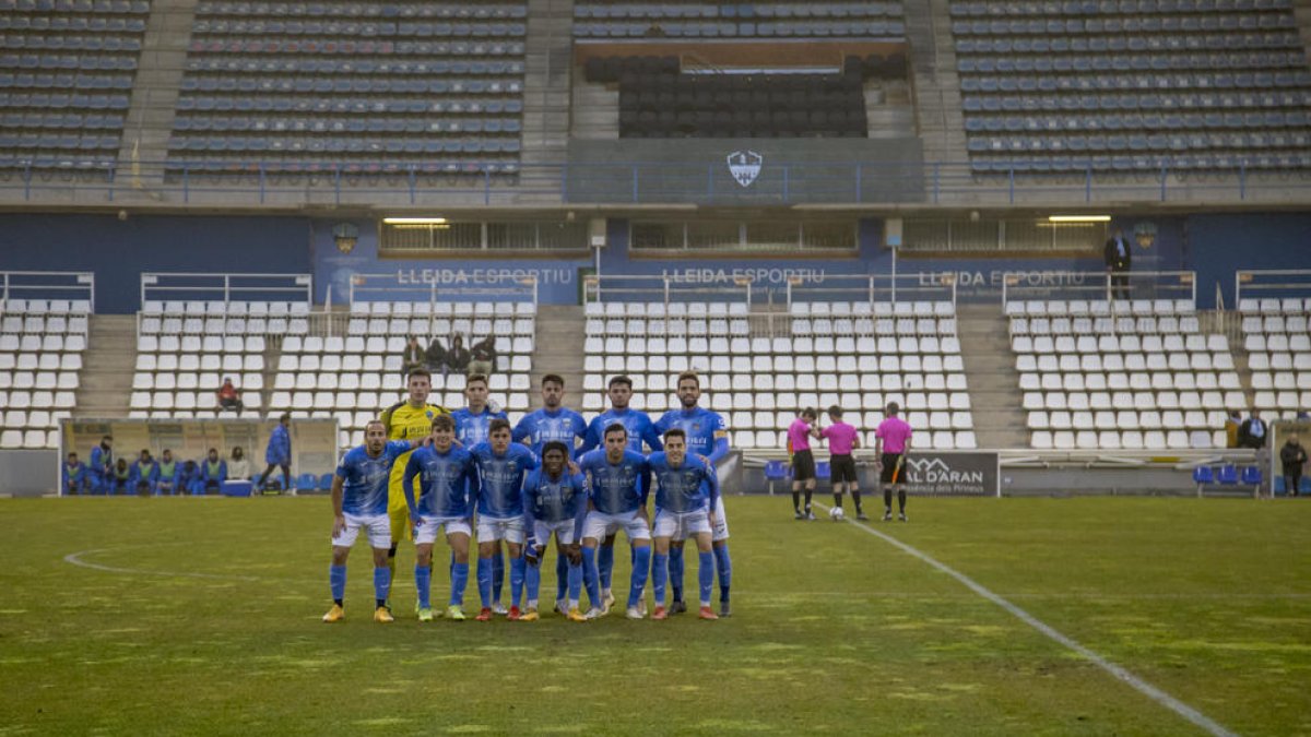 Los once titulares del Lleida ante el Brea posan antes del partido con el palco vacío al fondo.
