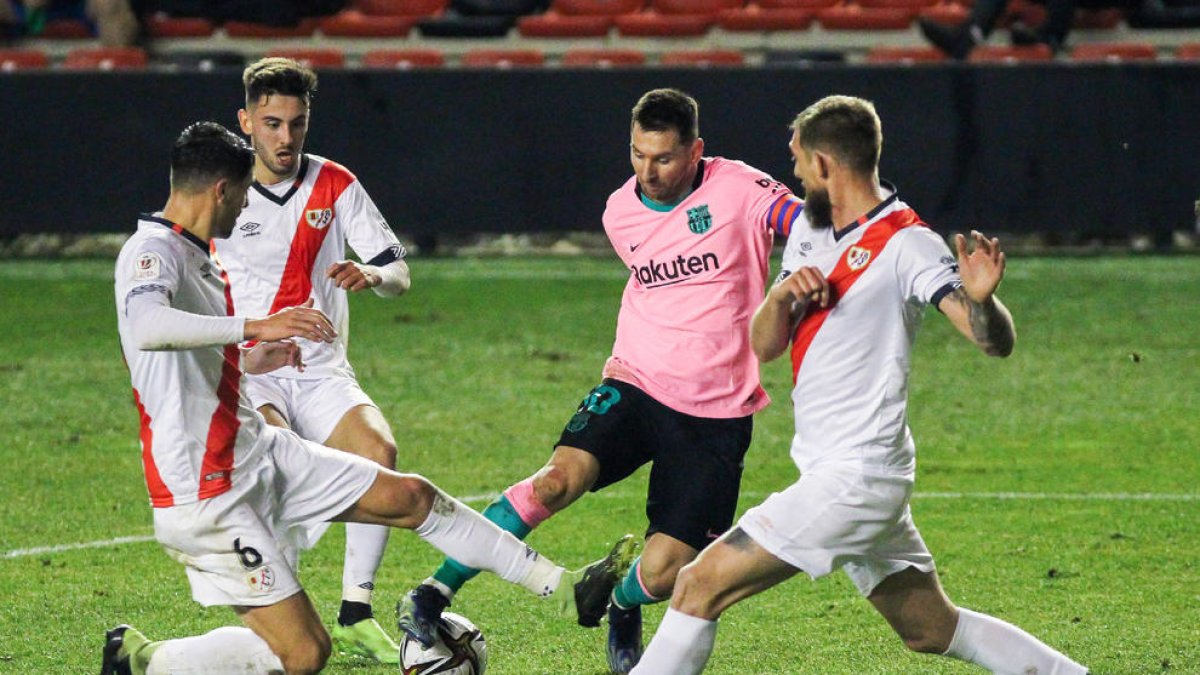 Leo Messi, envoltat per tres defensors del Rayo Vallecano, va tornar ahir després de complir la sanció per l’expulsió a la Supercopa.