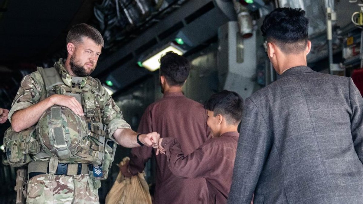 Un militar britànic saluda un menor afganès a punt d’embarcar en un avió que el traurà de Kabul.