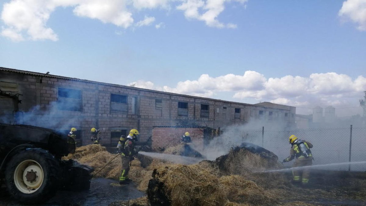 Los Bomberos sofocando el incendio en la balas de paja.