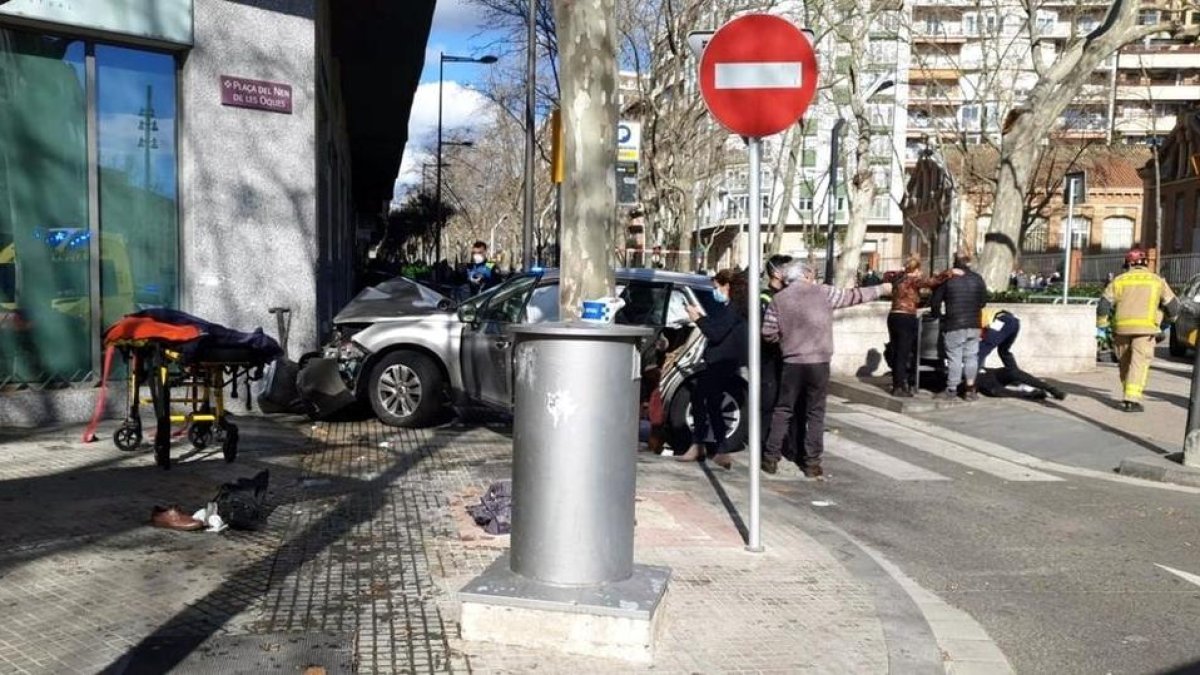 El vehicle després de xocar amb un edifici i els serveis d’emergències atenent un ferit.