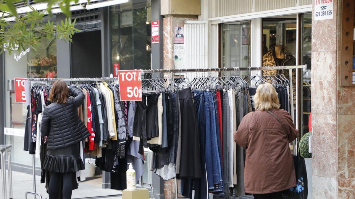Dos mujeres ante la parada de uno de los comercios que participa en la iniciativa “Rebaixes al carrer”.