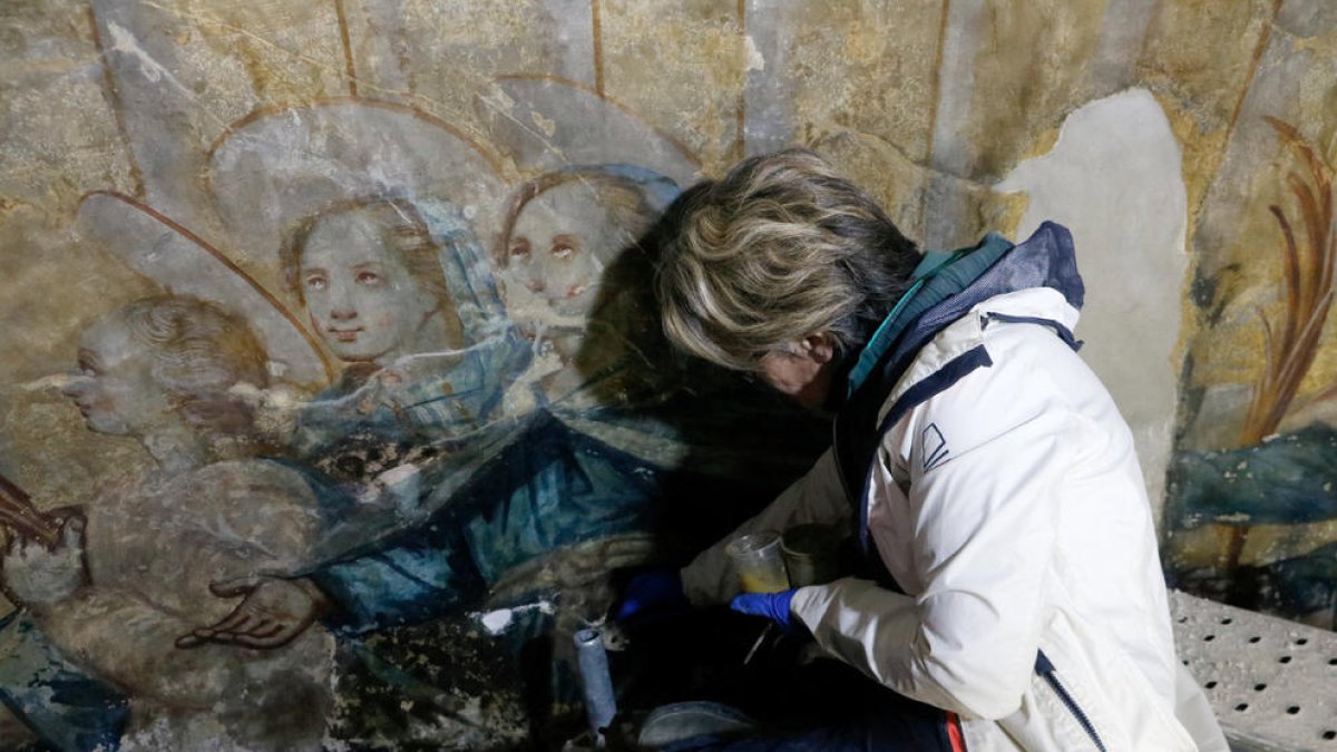 Treball de restauració en una de les imatges del mural.
