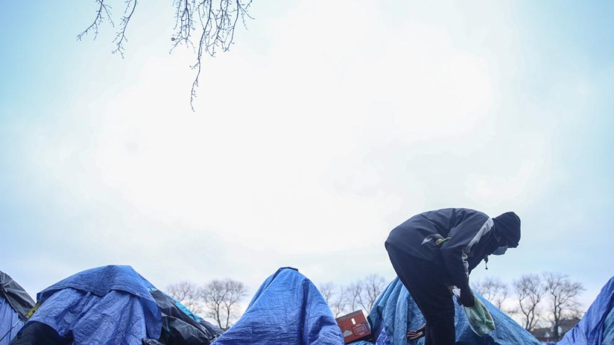 Un migrant busca entre les tendes d’un campament instal·lat a Calais.