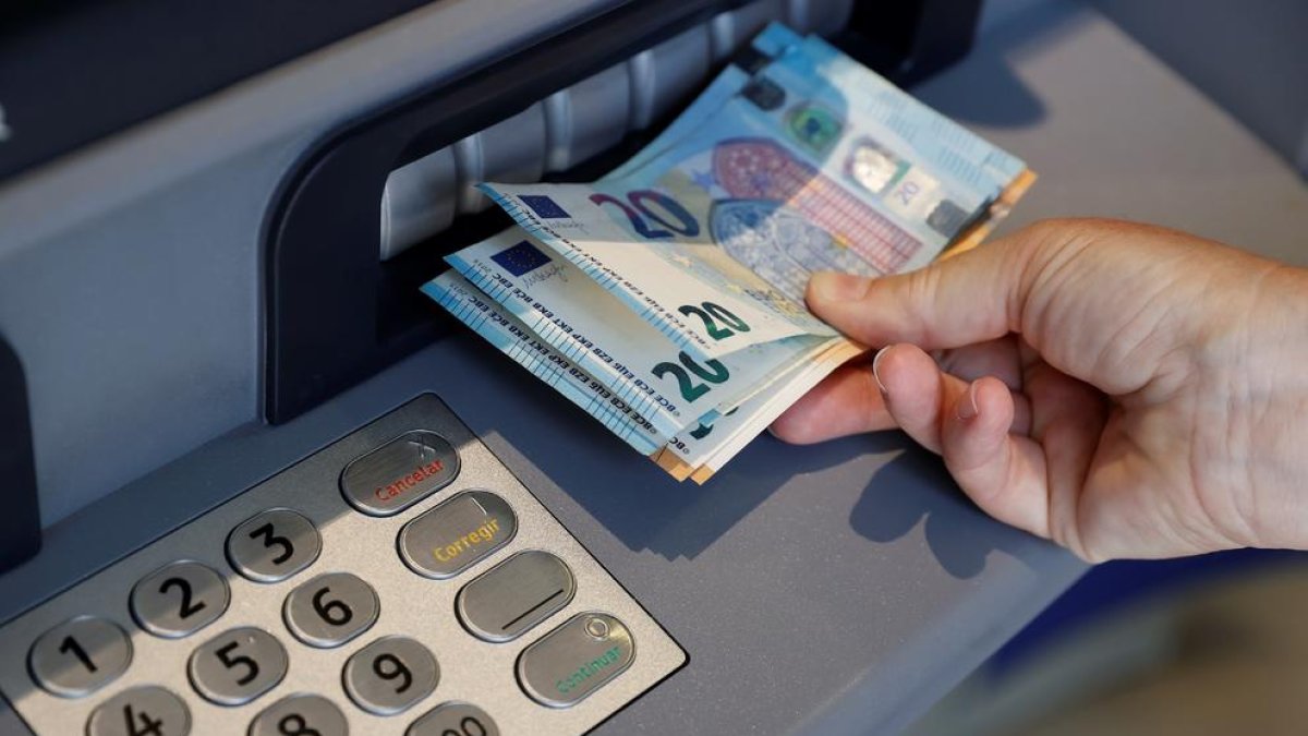 Imatge d’una persona traient diners d’un caixer automàtic.
