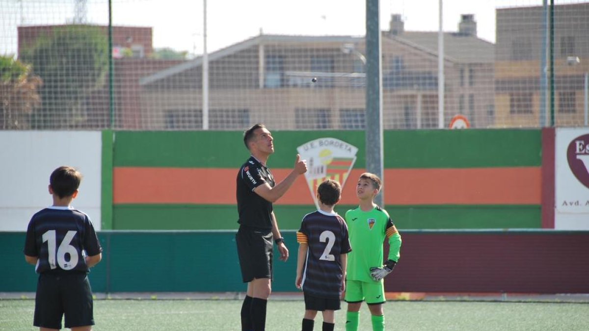 Xavier Estrada lanza la moneda para el sorteo de campo ayer en el Bordeta-Alpicat de benjamines ante su hijo Marc, de frente.