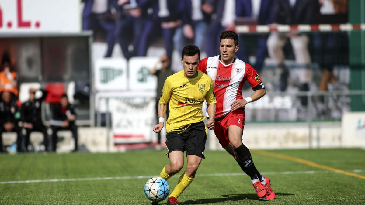 Un jugador del Mollerussa controla y protege el balón ante un defensa rival.