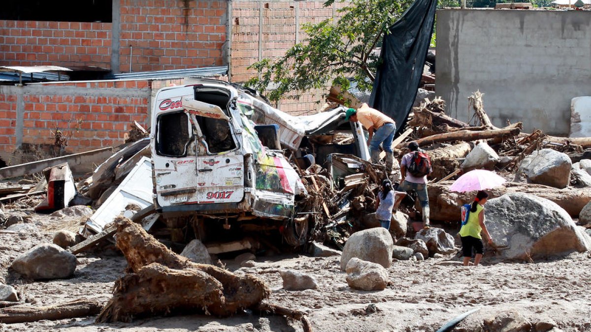 Habitants del barri San Miguel observen un vehicle destruït.