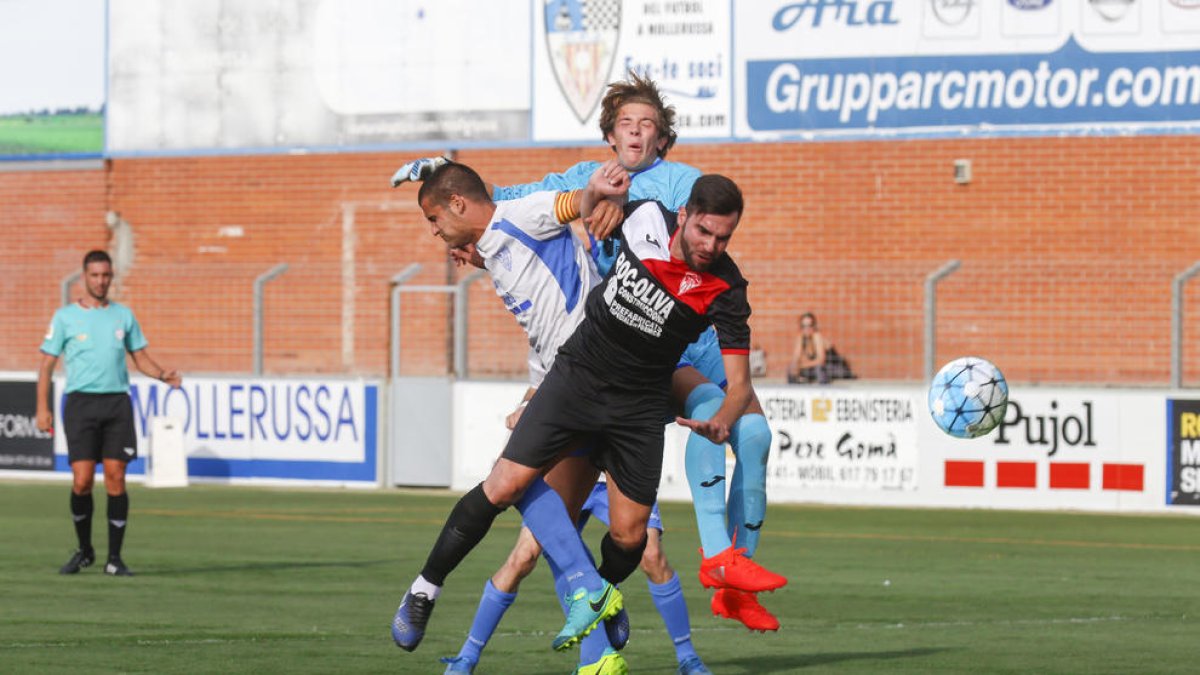 El porter i un defensa del Linyola pugnen la possessió amb un jugador del Mollerussa.