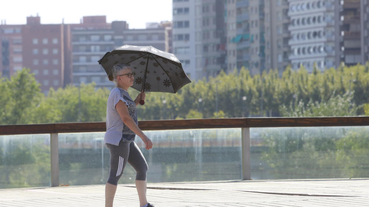 una dona es protegeix del sol amb un paraigua a Lleida en una imatge d'arxiu