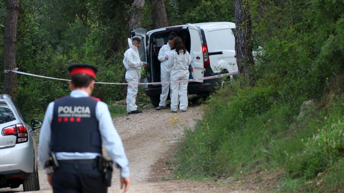 La policia preparant-se per arribar al cotxe calcinat.