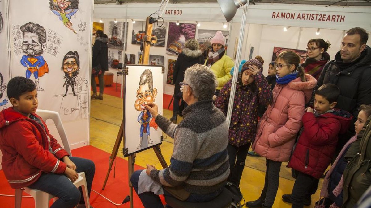 Uno de los artistas que participan en la muestra dibujando la caricatura de un niño.
