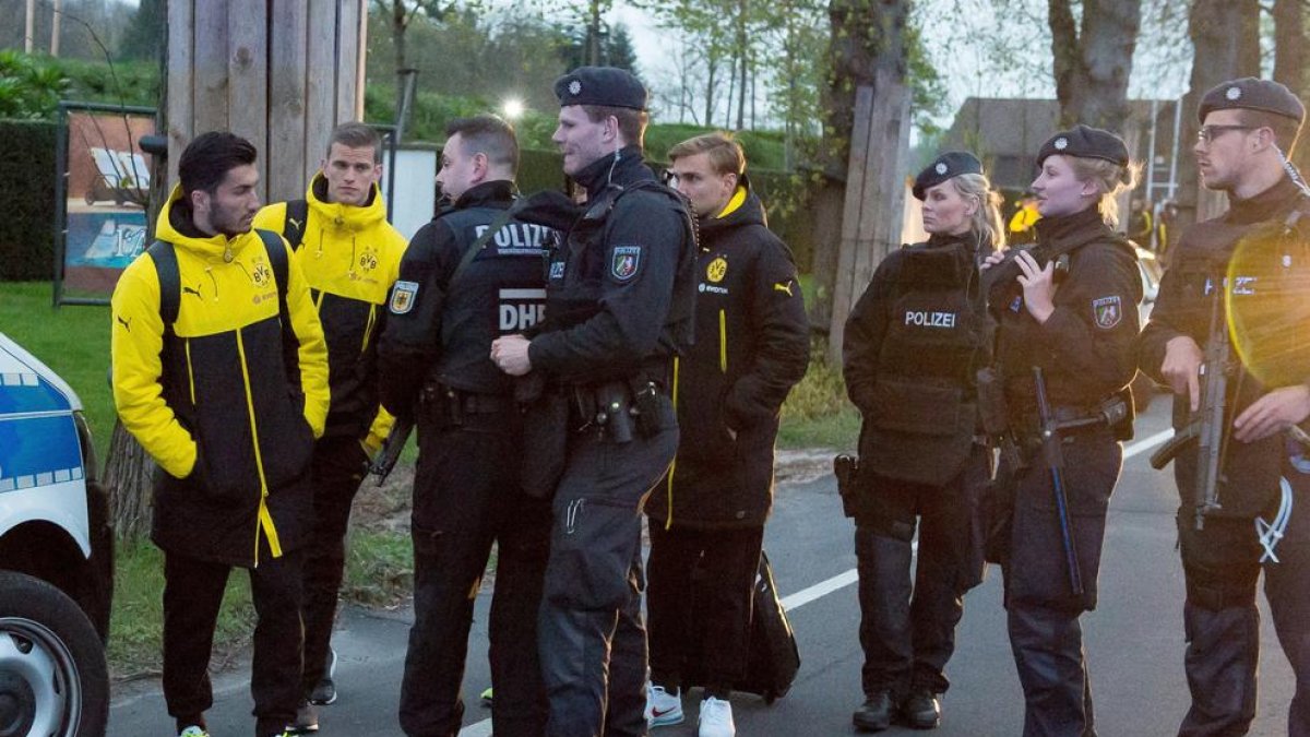 Jugadors del Borussia Dortmund, al costat de policies fortament armats després de l’atemptat contra l’autobús de l’equip.