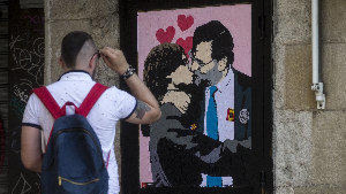 Un artista urbà pinta Rajoy i Puigdemont besant-se a prop de la Generalitat