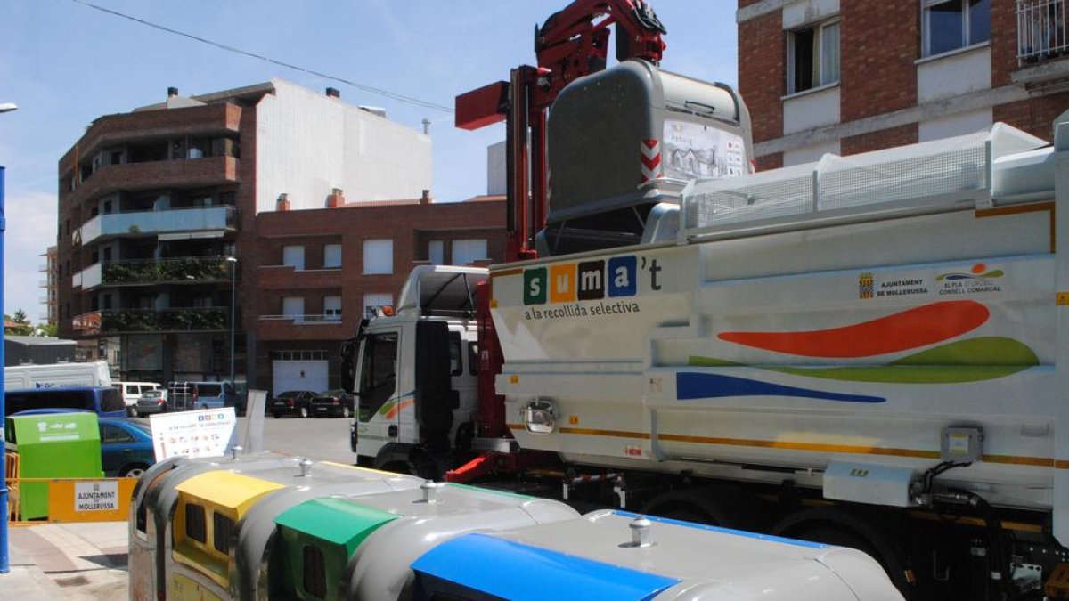 Un camión, haciendo la recogida de un contenedor de basura.